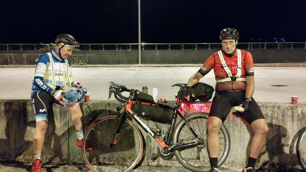 Luis, refilling one of his bottles with water, and Dani eating something while listening to a conversation