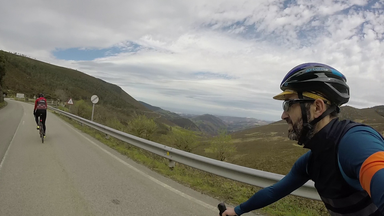 Me and dani, starting to pedal a bit faster and going down a garganta. The view shows the valley, hills on both sides and the cantabric sea at the end of the valley.