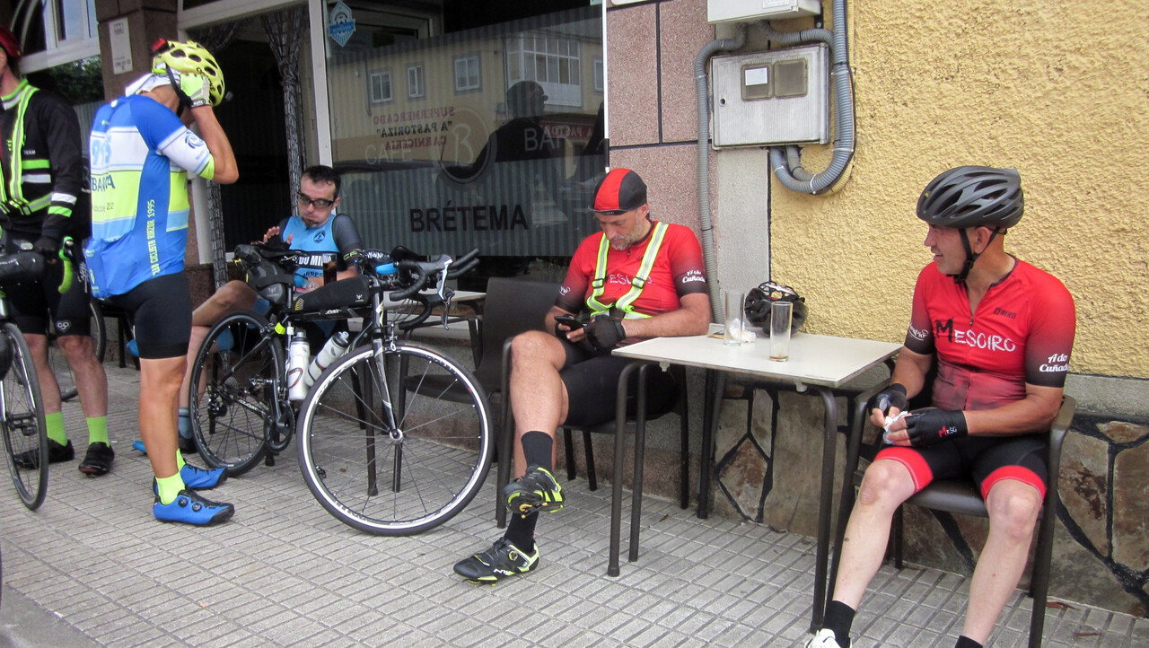Manolo, me, Dani and Jose, sitting outside the café in a pastoriza, eating something and looking at our phones.