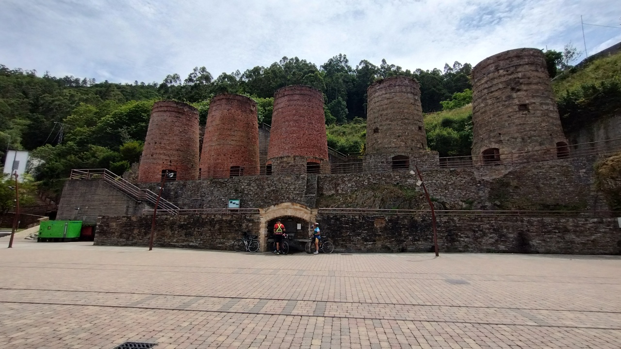 Cesar, Dani and Jose refilling their bottles at the fountain in the square with the old furnace chimneys in A Pontenova