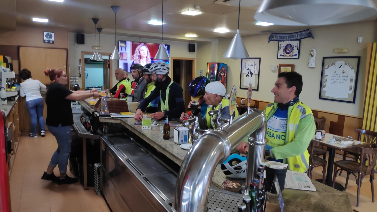 The counter of the bar in Allariz, filled with randonneurs placing orders for breakfast. There are two waitresses behind the counter preparing the stuff we ordered