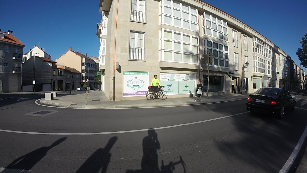 Dani, with his bike, leaning against the wall of a 3-storey building, sunbathing