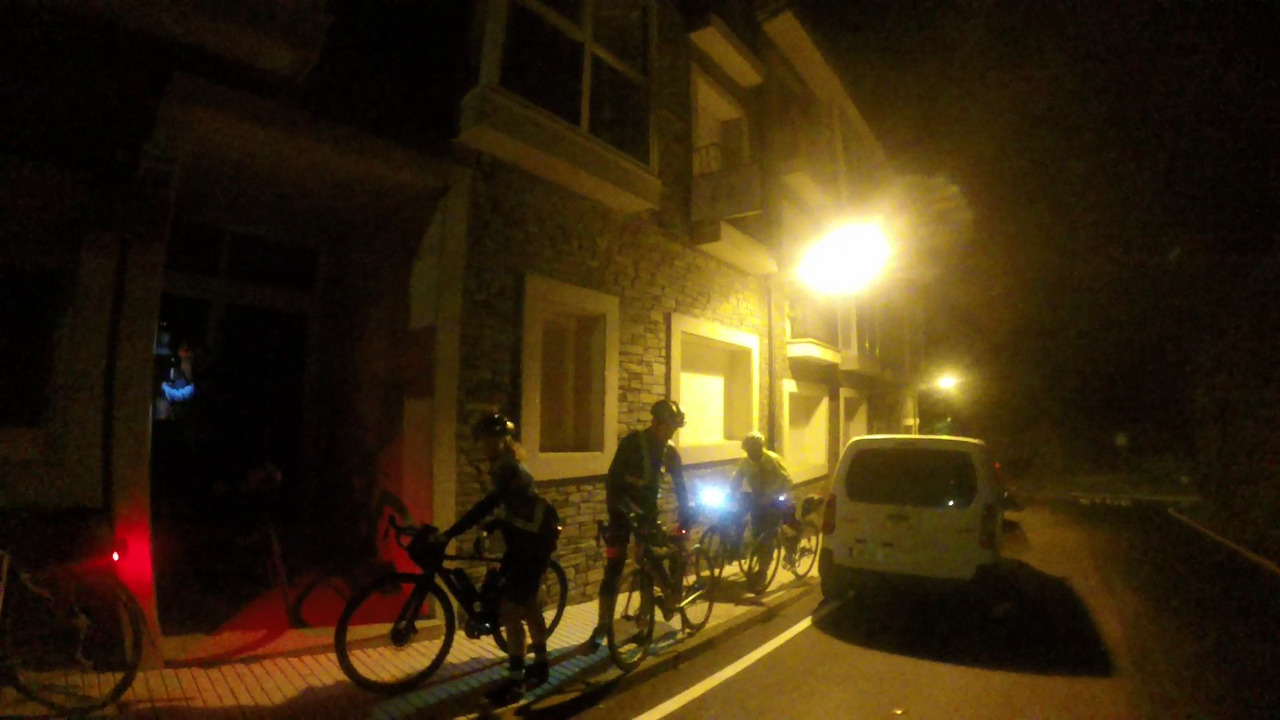 Estefanía, Roberto and Valentín, getting their bikes into the entrance to the appartment in O pedrouzo, at night
