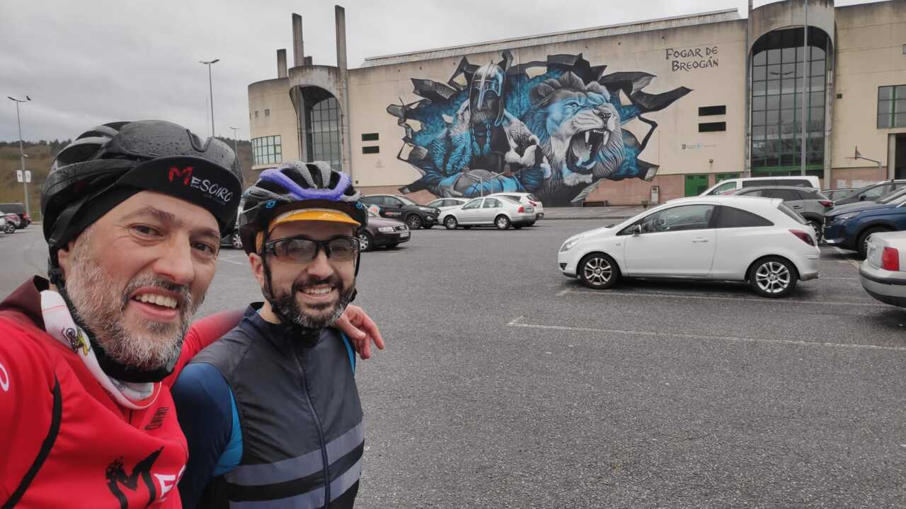 Dani and me, back at the starting point, wet and cold, but happy. The photo was taken in the exact same spot as the one before leaving this morning, with the same big graffiti on the back, the roman warrior and the lion by the message Fogar de Breogan
