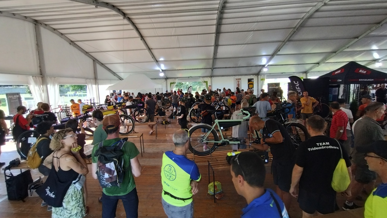 An look of the concours de machines from the entrance, with several bikes on stands and a lot of people around them