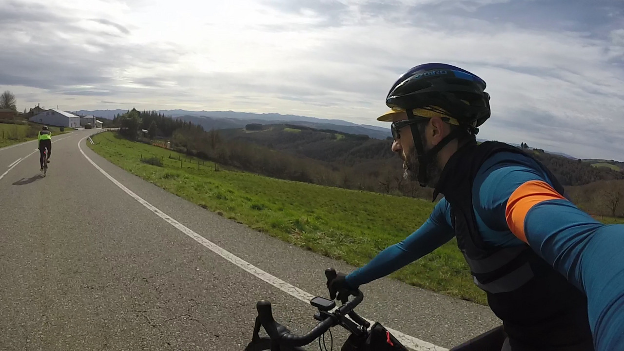 Dani, far away, on the left and me on the right, riding on a road with open views to our right