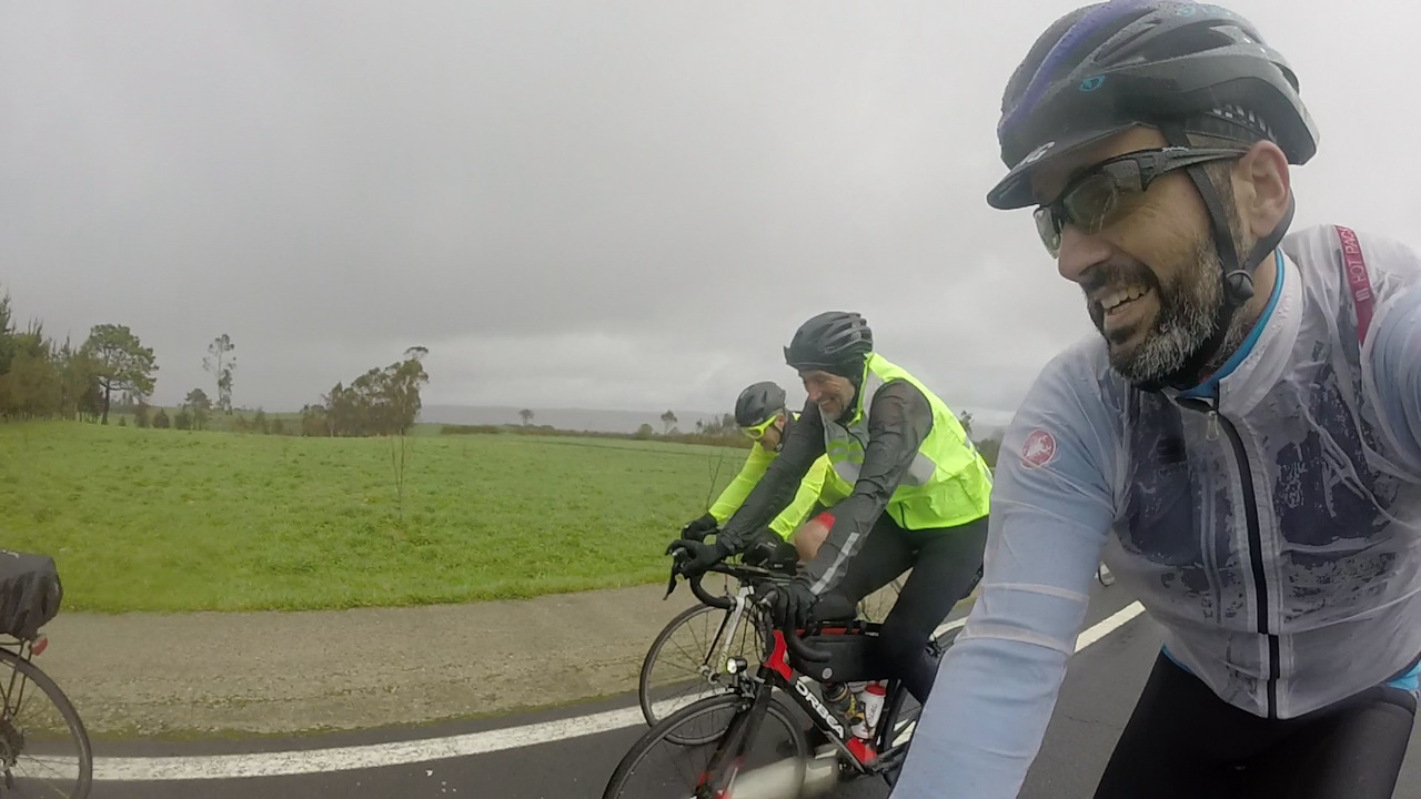 Me on the right side, completely soaked but with a smile on my face. Dani pedals by me, also with a big smile on his face and Oscar is a bit behind him.