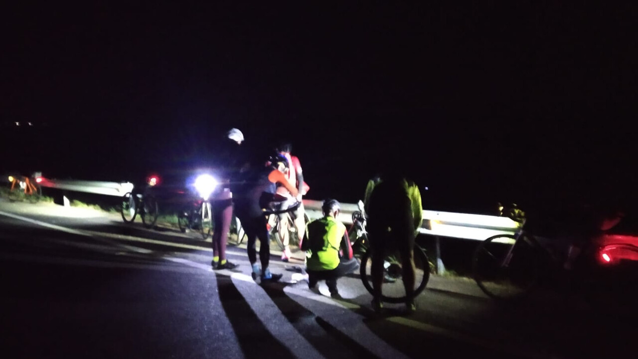Our group stopped in the middle of the night by a rail on the road, I'm replacing the inner tube in my front wheel, while Dani is replacing the one in my rear wheel