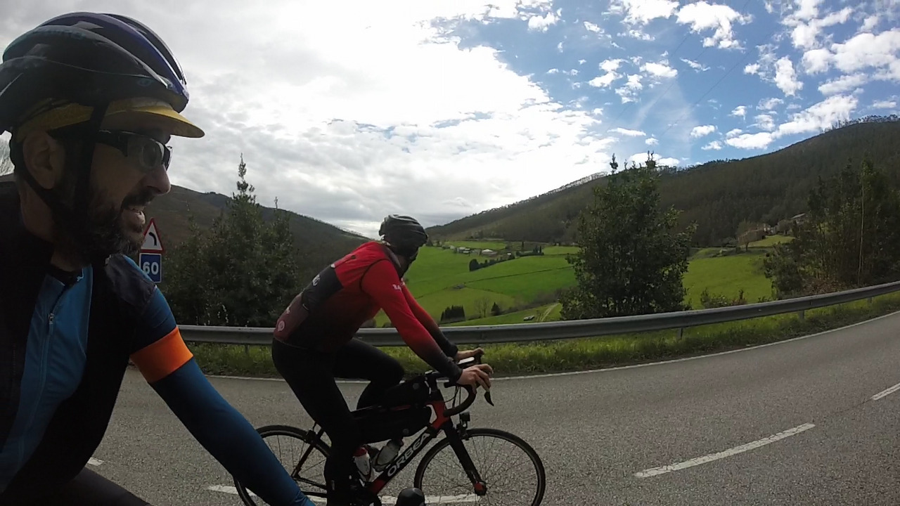 Dani and me riding on that same road as the previous picture, this time the photo was taken from the right so both of us are on camera. The top of the hills and small mountains on our left are visible, as well as the cloudy sky
