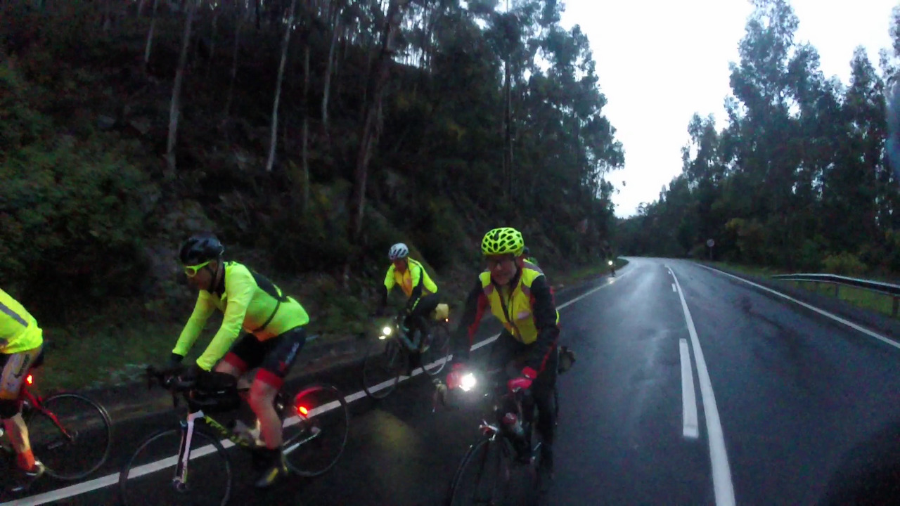 A group of randonneurs, riding up the first climb of the day, under some strong rain