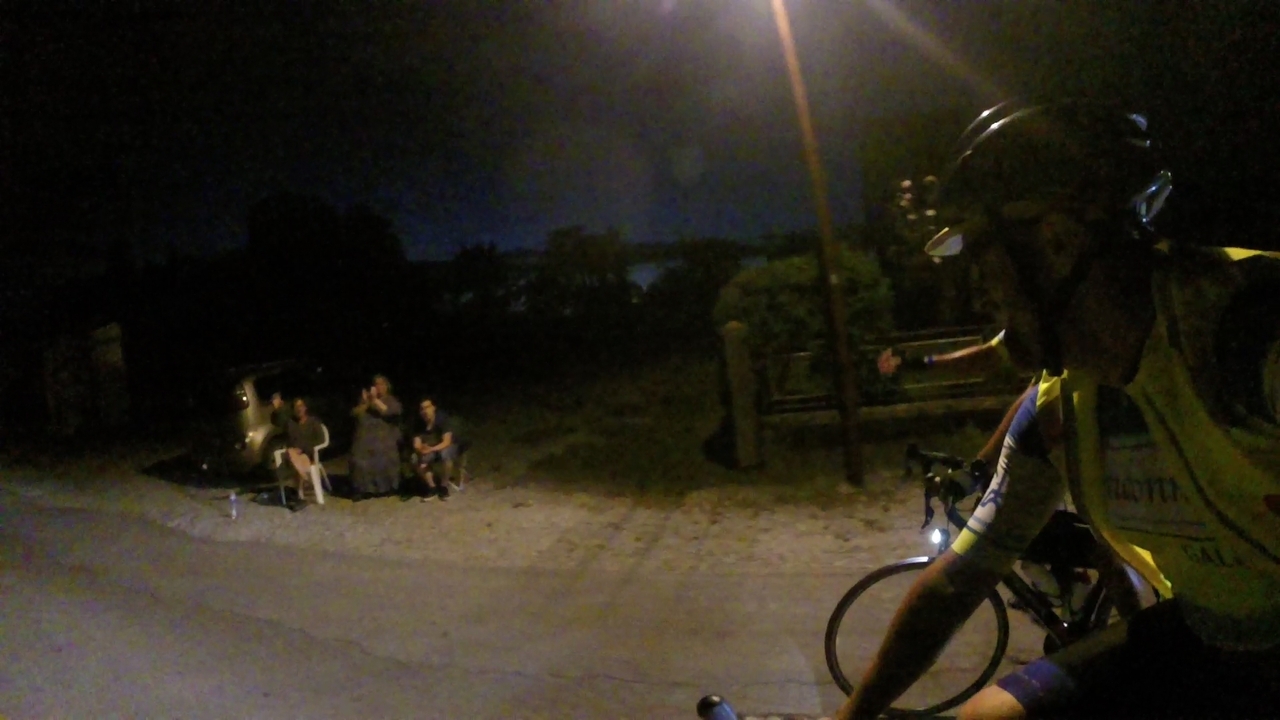 Some people seating by the road, watching the riders passing by and cheering us up