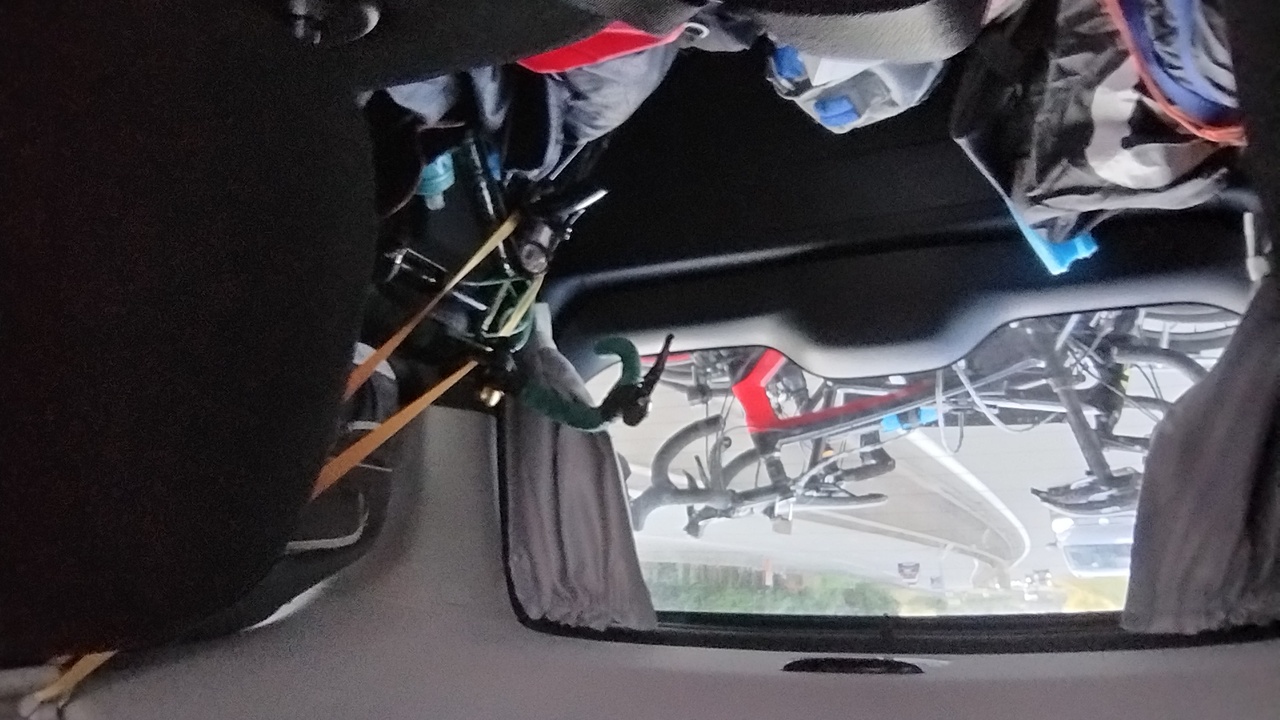 Picture taken from the back seat of the van, but backwards, showing our luggage in the back of the van, ferreiro's bike also in the back of the van and the other bikes in the bike rack outside