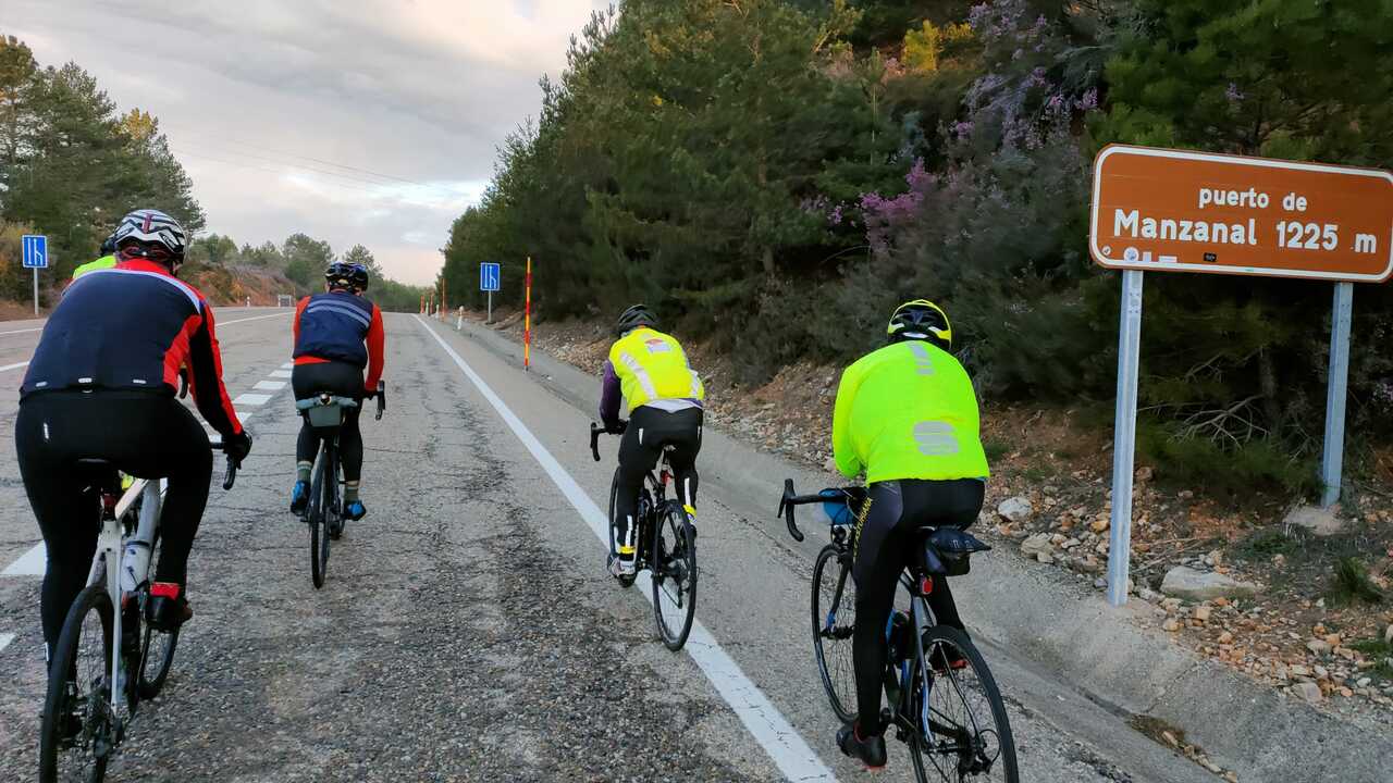Juankar, me, Cesar and Anselmo riding our road bikes by the sign that says 'puerto de Manzanal 1225 m'
