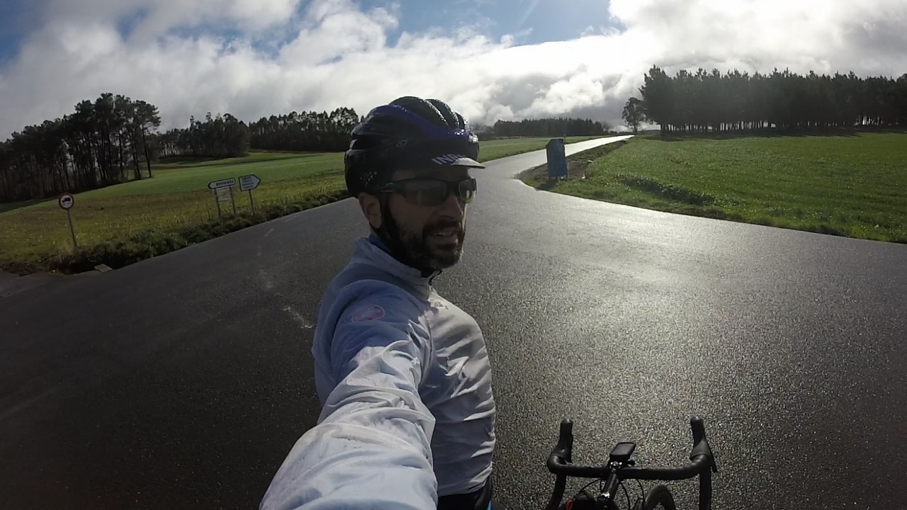Me at the crossroads, the sun shining and light reflecting on the weat roads, with fields and trees all around