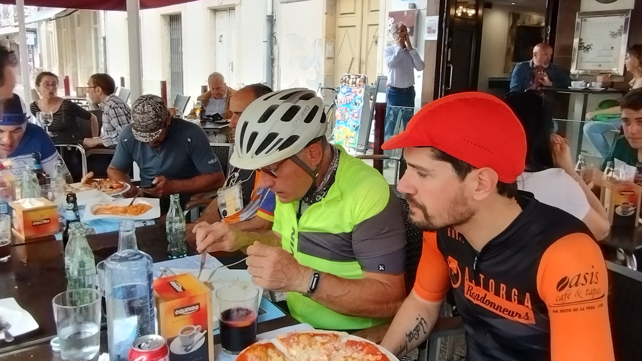 Valentin and Sergio, having lunch. Sergio is having a huge pizza, everybody looks busy either eating or checking their phones