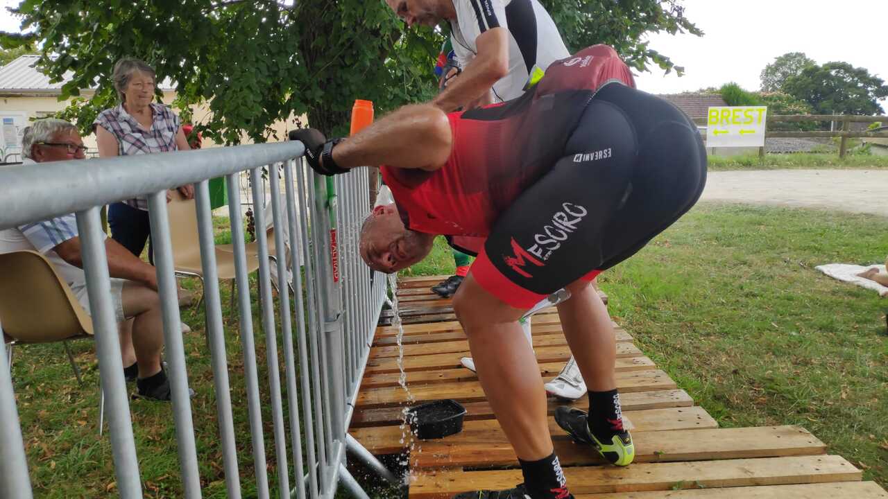 Dani, crouching below a water tap, with it open and water pouring over his head