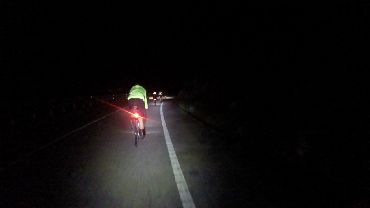 The group, riding at night, keeping a straight line