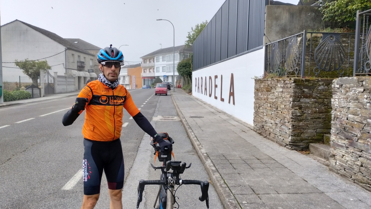 Roberto, holding his bike, by the big letters on a wall: P A R A D E L A