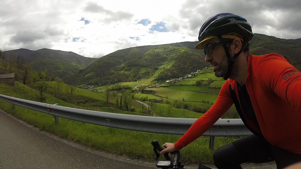 Selfie of myself, taking from my left side while cycling up to El Puerto. Behiind me there are views of the valley below, all green and hilly with a few houses here and there and small twisted roads going towards the hills at the back