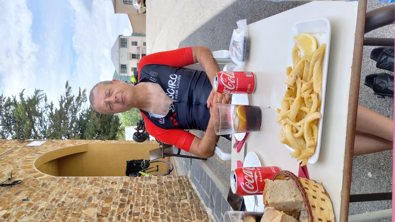 Oscar, seating at the table in Casa Diego's terrace in Santa Eulalia, with a plate of Calamares fritos in front of him