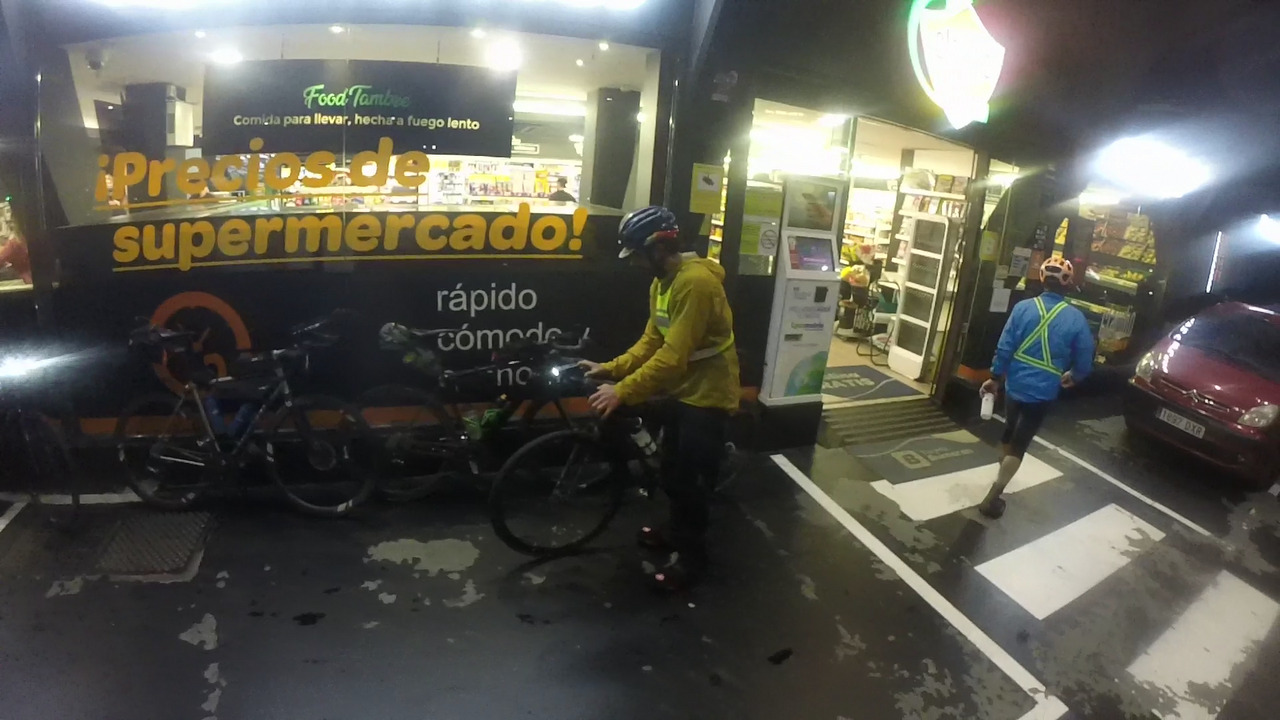 Sergio Pulido, parking his bike on the wall at the gas station in santiago. Saúl is going towards the entrance of the supermarket