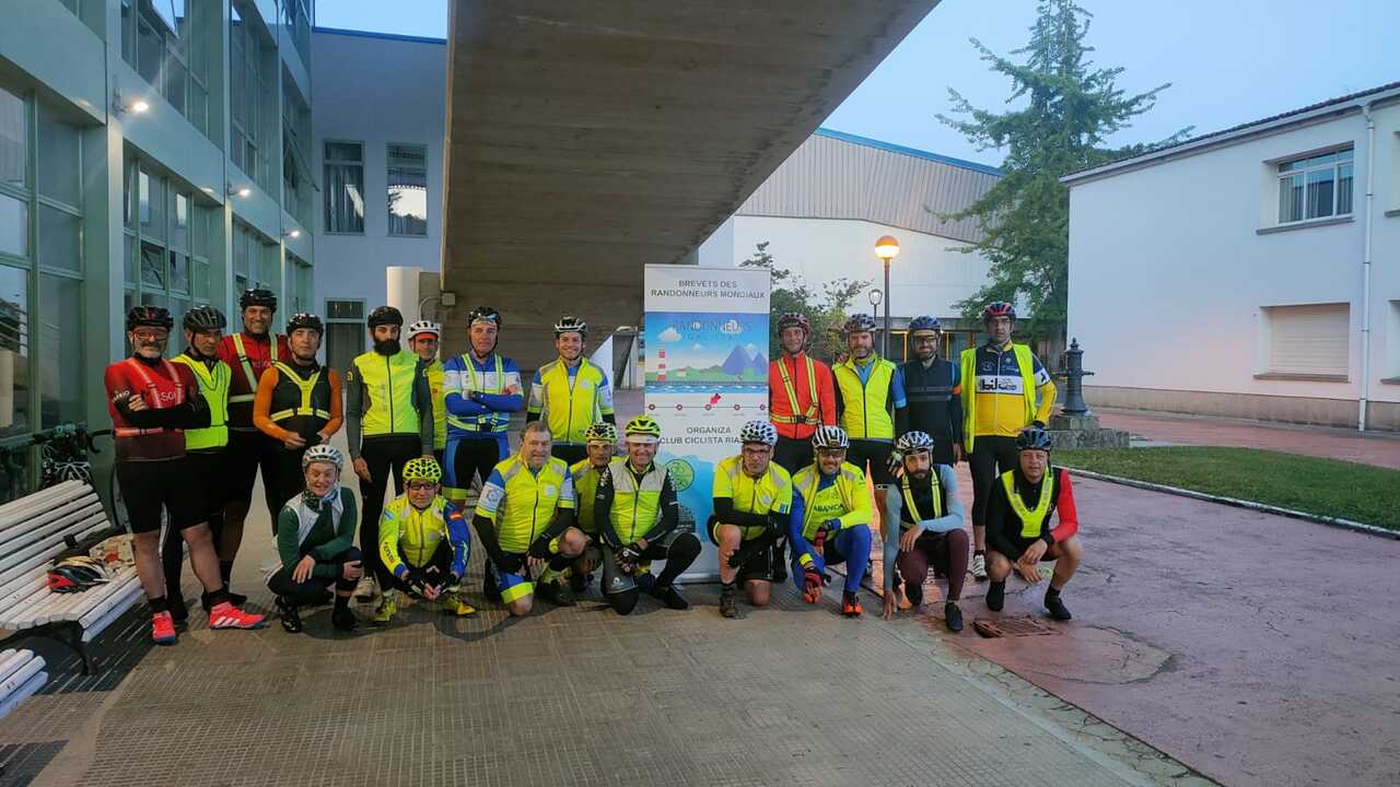 The whole group of randonneurs posing with a big flyer made for this Brevet