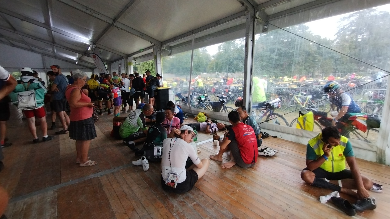 Randonneurs sitting inside one of the tents, protected from the rain