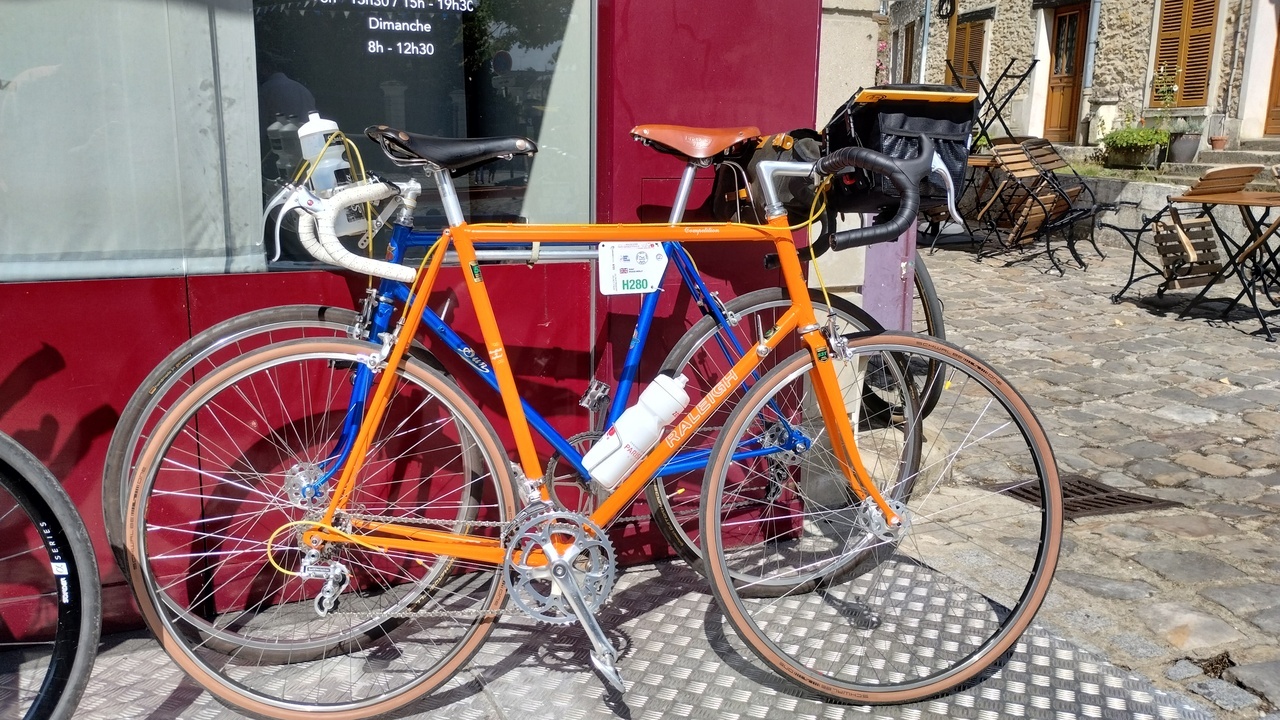 A couple of classic, old-style, steel bikes, blue and orange.