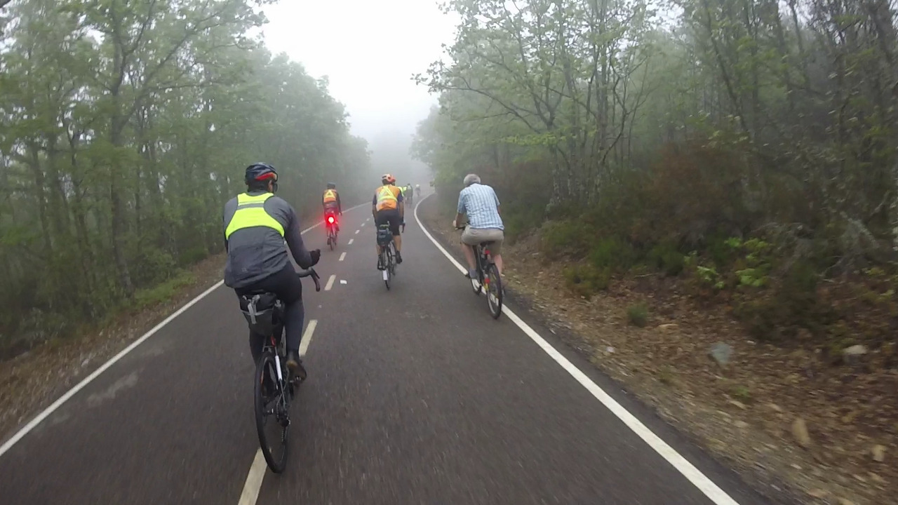 Sergio, Roberto and Saúl, riding alongside the pilgrim doing el camino on a city bike, wearing normal clothes and sandals