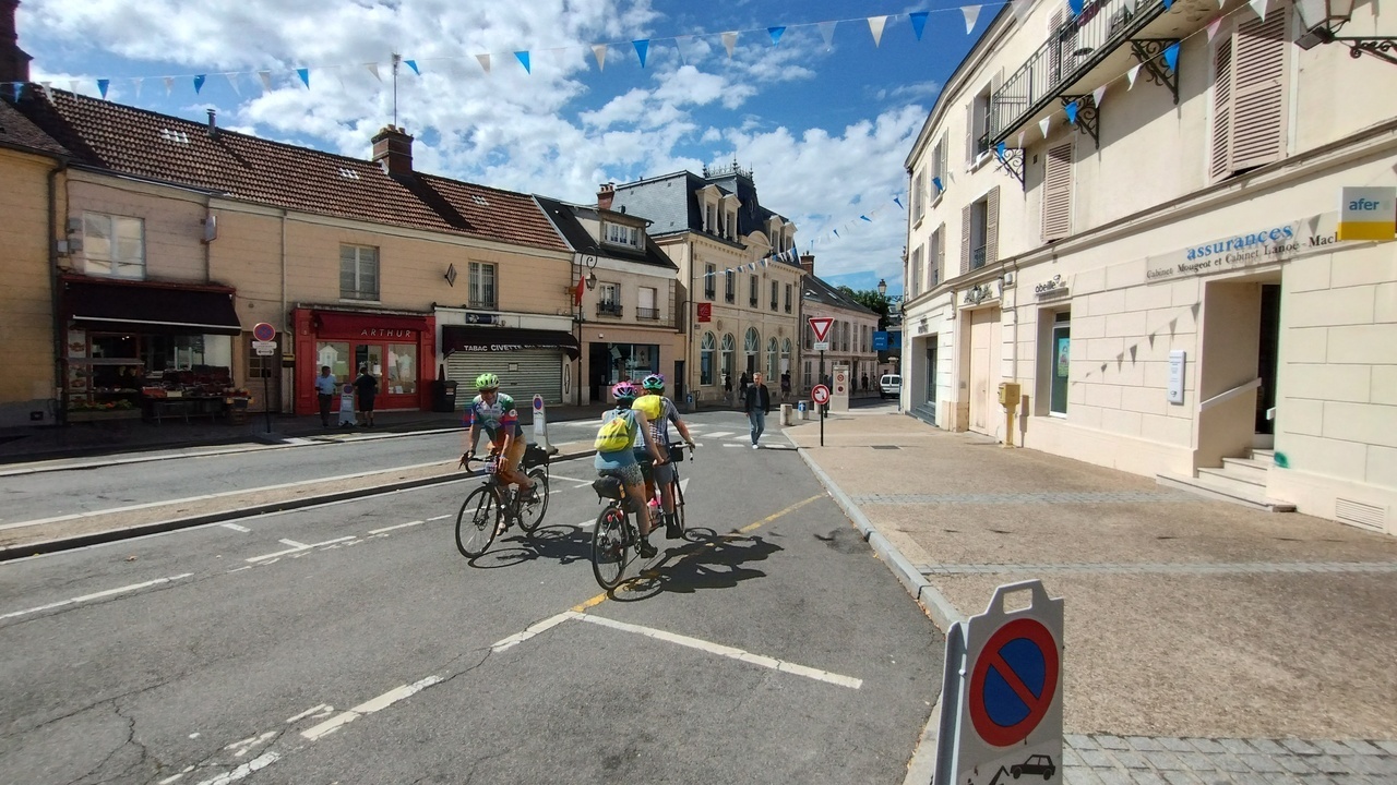 A couple, riding a tandem on one of the streets in Rambouillet, another bike is passing by them