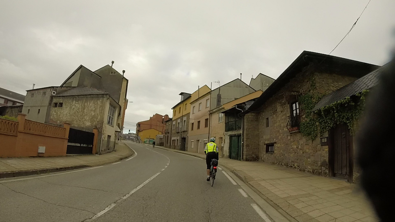 Ferreiro riding towards the entrance of Toreno, small houses on both sides of the road