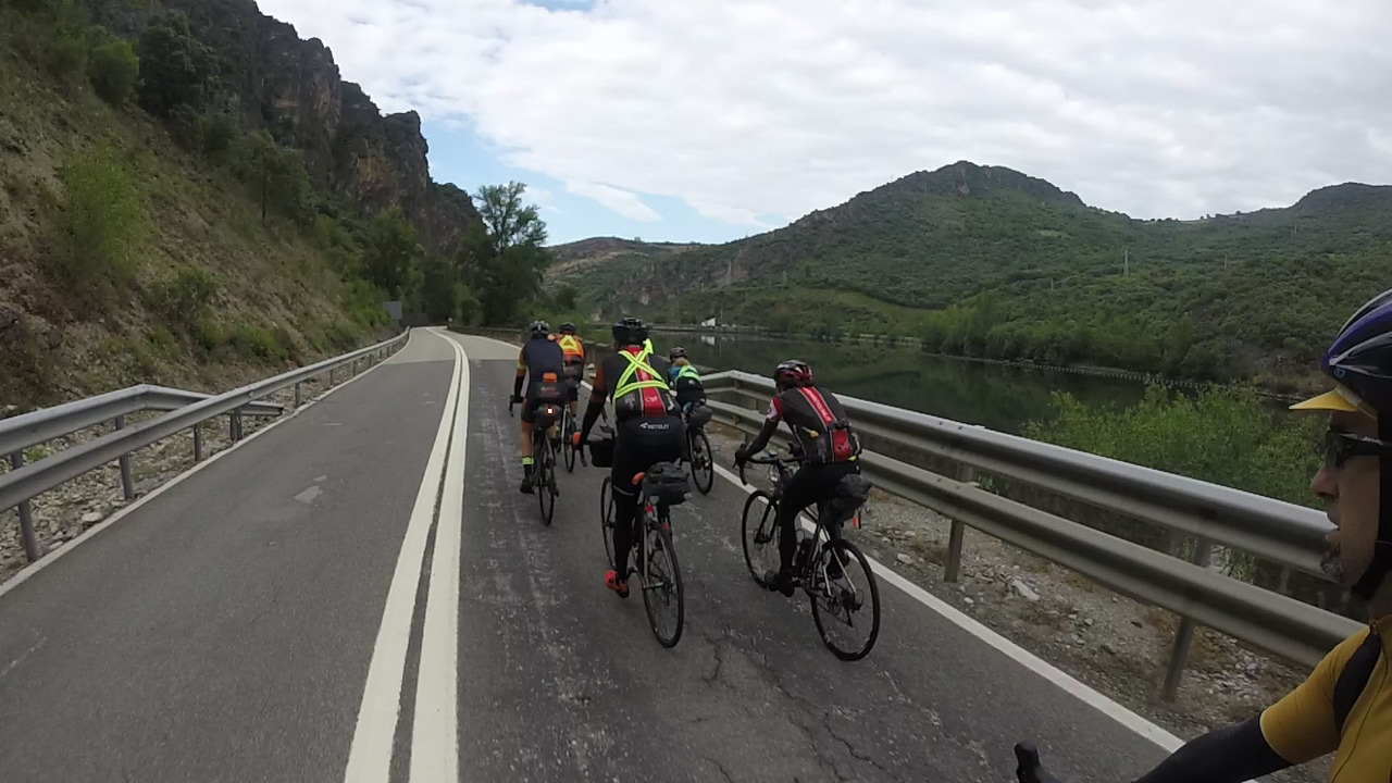 The group, riding fast after leaving the tunnel behind, going on the road by the river Sil and the dam of Peñarrubia