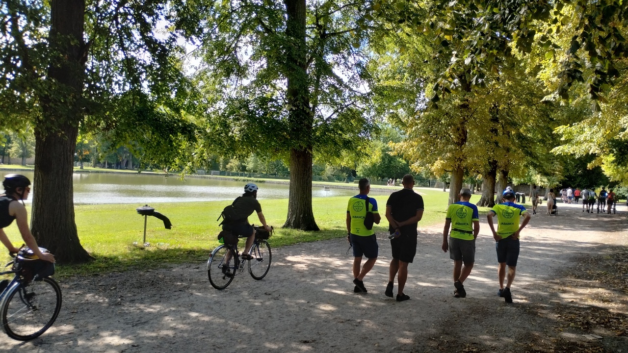 The guys, walking on a path through the gardens, on direction to the castle of Rambouillet, some cyclists are passing by them on the same direction
